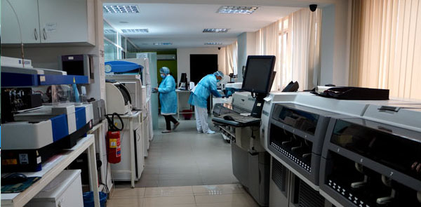 Salle technique du laboratoire : automates d'analyses et techniciennes en tenue de protection